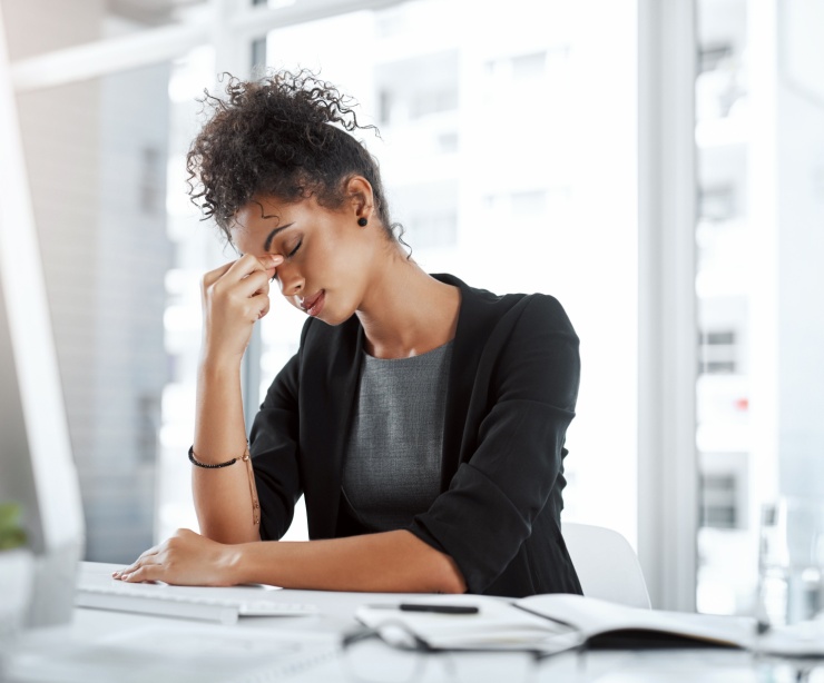 A woman pinching the bridge of her nose in an office.