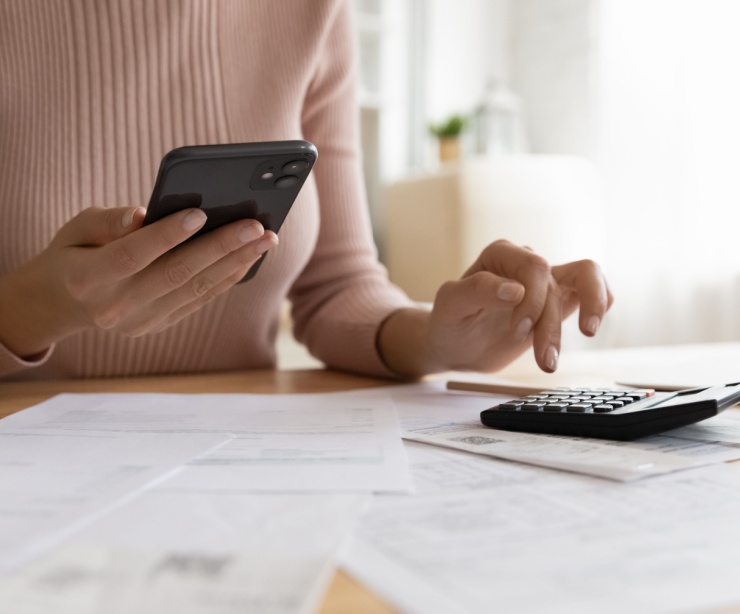 A woman using a phone and calculator.