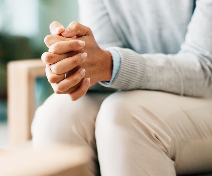 A woman sitting with her hands clasped.