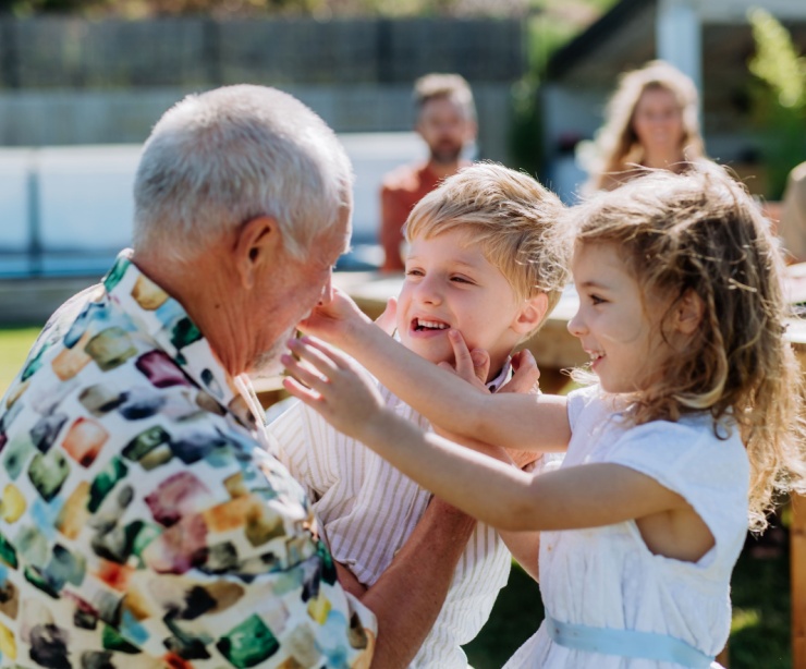 A grandfather playing with his grandchildren outdoors.
