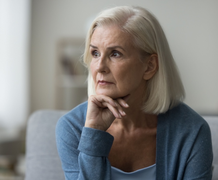 An older woman looks pensively off to one side.