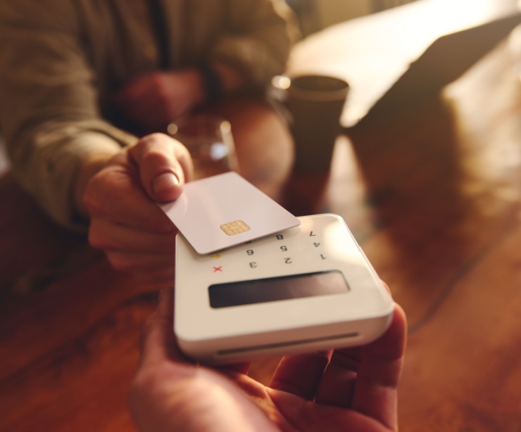 A person using their debit card to pay in a café.