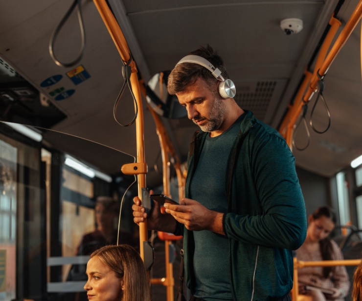 A man travelling on a bus with headphones on.