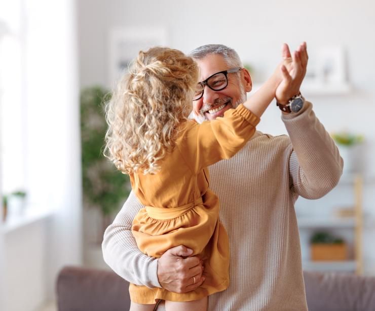 A grandfather playing with his granddaughter at home.