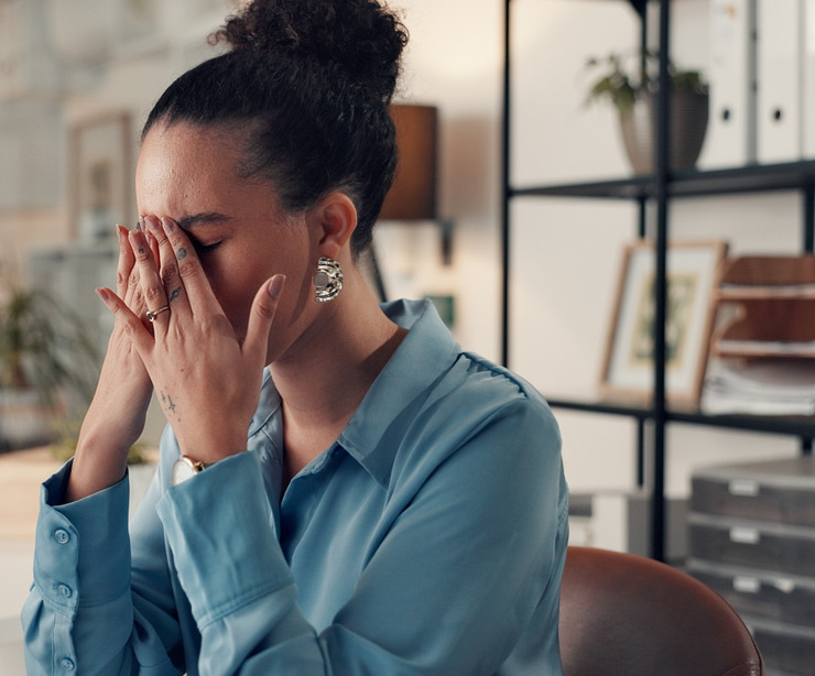 A woman sitting at a desk and looking stressed.