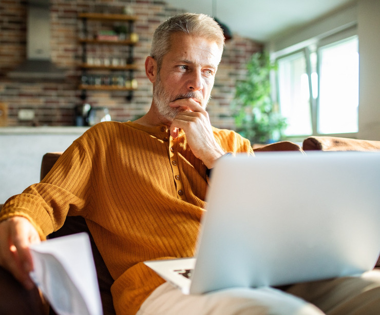 A man in his 50s thinking while using a laptop