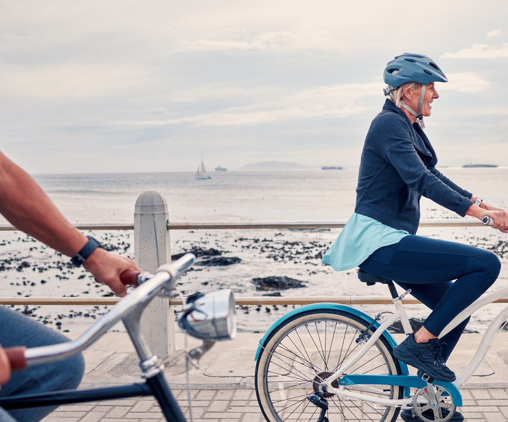 A woman cycling along a beachfront.