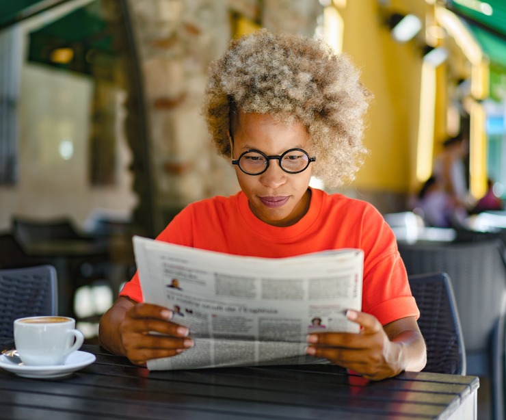 A woman reading a newspaper in a café.