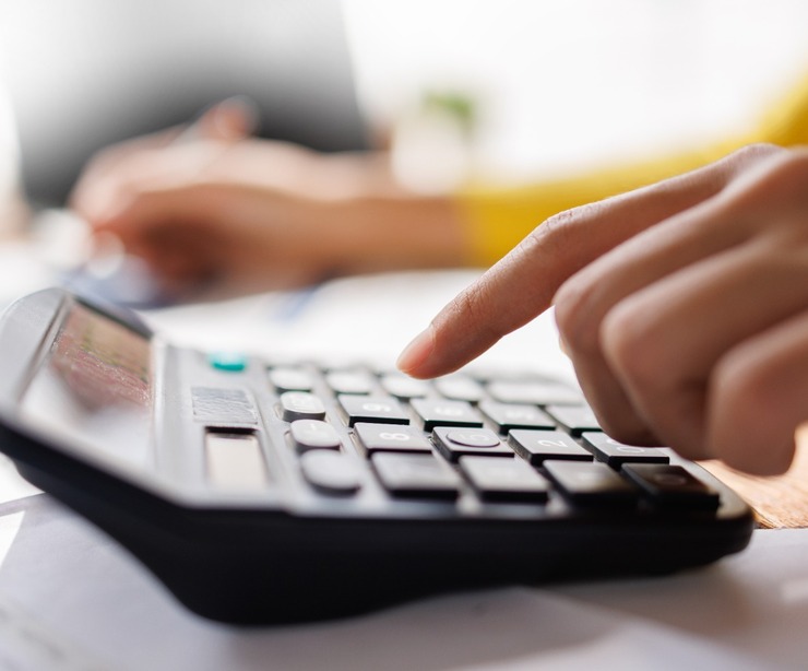 A person using a calculator while reviewing paperwork.